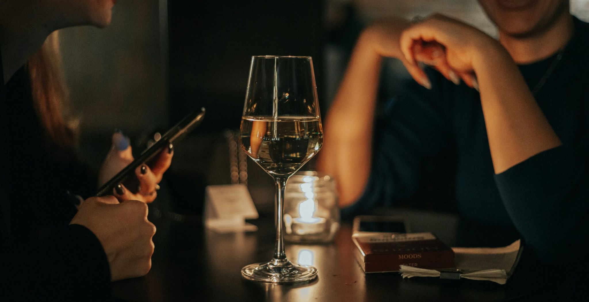 Oberon Two women seated at a table, enjoying a glass of wine together in a cozy setting.